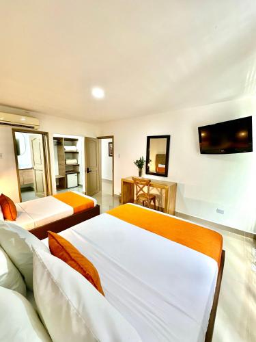 a bedroom with two beds and a tv on the wall at Hotel Cafe Cafe Avenida in Armenia