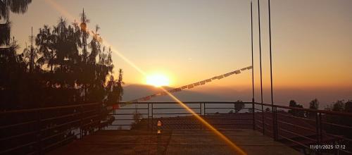 a sunset behind a fence with the sun in the background at Everest Home Stay Temal Kalimati Tower in Thapathali
