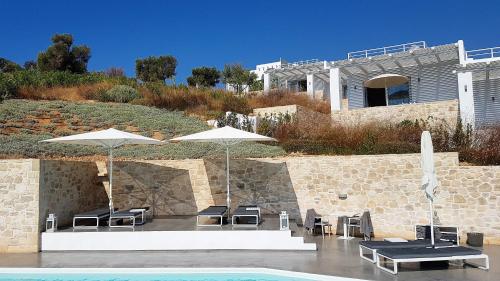 a group of chairs and umbrellas next to a pool at Galini Breeze in Agia Galini
