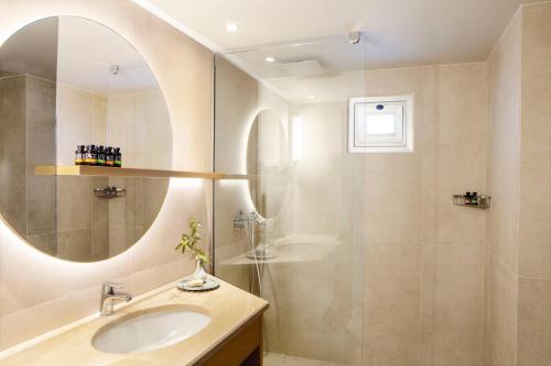 a bathroom with a sink and a shower with a mirror at Mirabello Bay Luxury Resort in Agios Nikolaos