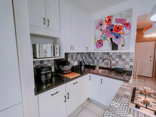 a kitchen with white cabinets and black counter tops at OCEAN SHOREBREAK - Umdloti resort - Back up Water in Umdloti