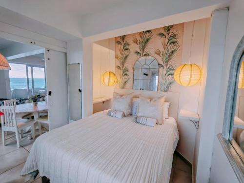 a bedroom with a white bed and a dining room at OCEAN SHOREBREAK - Umdloti resort - Back up Water in Umdloti