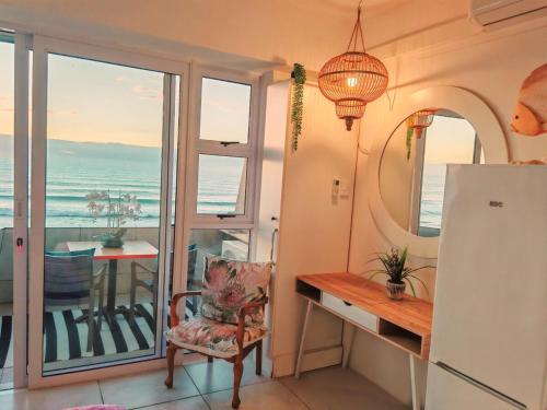 a room with a table and a chair with a view of the ocean at OCEAN SHOREBREAK - Umdloti resort - Back up Water in Umdloti
