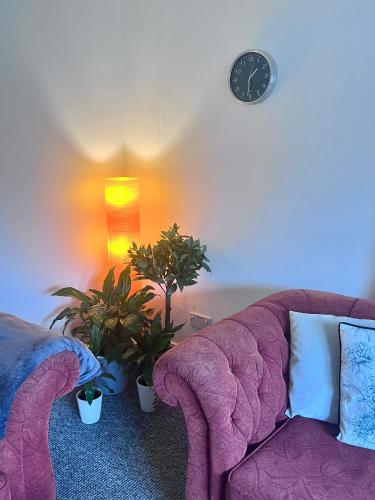 a living room with a purple couch and a clock at River house in Birnam
