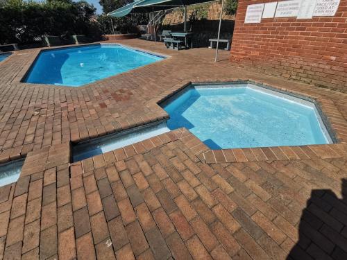 a large swimming pool in a brick yard with a brick building at OCEAN SHOREBREAK - Umdloti resort - Back up Water in Umdloti