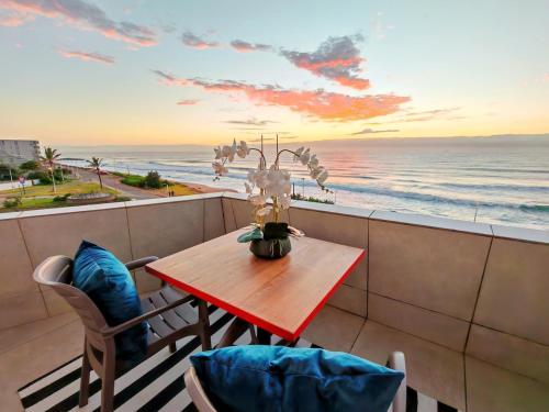 a table and chairs on a balcony with a view of the ocean at OCEAN SHOREBREAK - Umdloti resort - Back up Water in Umdloti