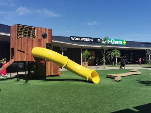 a yellow slide in the grass in front of a building at OCEAN SHOREBREAK - Umdloti resort - Back up Water in Umdloti