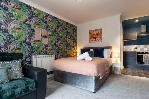a bedroom with a bed and a green chair at Cosy Studio Apartment Town Centre Location in Middlesbrough