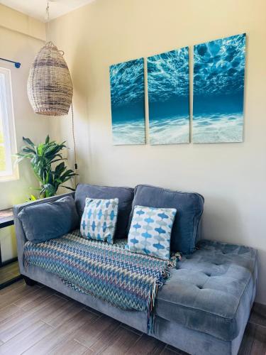 a blue couch in a living room with three paintings on the wall at Costa Nube in Caye Caulker