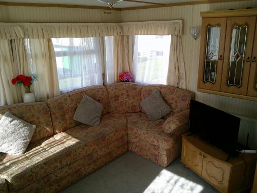 a living room with a couch and a television at Sealands Canberra 6 Berth Central Heated Access to the beach in Ingoldmells