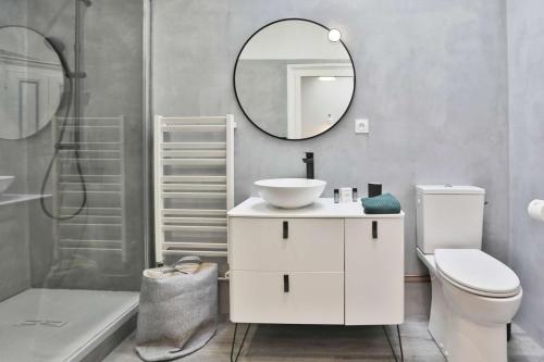 une salle de bain avec un lavabo, des toilettes et un miroir dans l'établissement Villa Napoléon, city center and seaside, à Les Sables-dʼOlonne