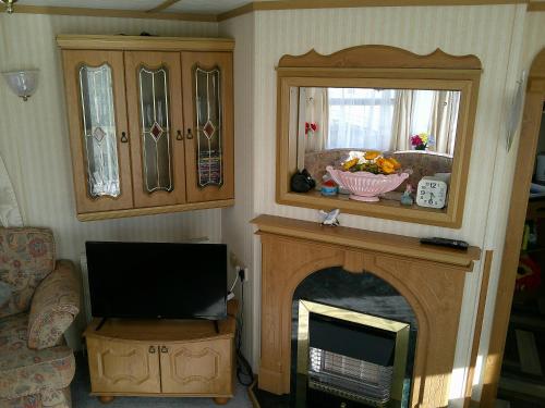 a living room with a tv and a fireplace at Sealands Canberra 6 Berth Central Heated Access to the beach in Ingoldmells