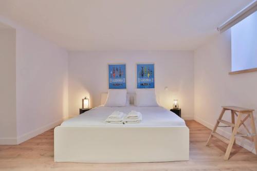 un lit blanc dans une chambre blanche avec un tabouret dans l'établissement Villa Napoléon, city center and seaside, à Les Sables-dʼOlonne