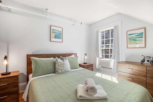 a bedroom with a green bed with a baby on it at Steps to Dining Less than 1 mile to Bayside Beaches in Dennis