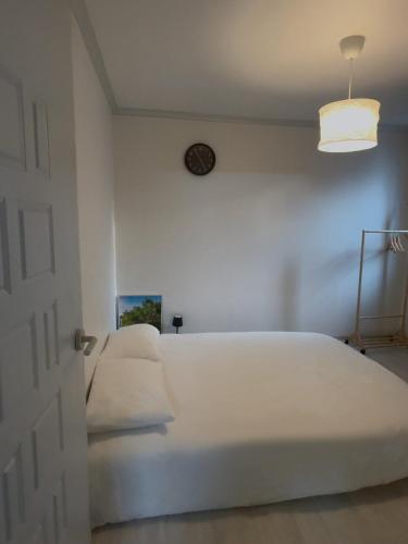 ein Schlafzimmer mit einem großen weißen Bett mit einer Uhr an der Wand in der Unterkunft Sky Haenggung in Suwon