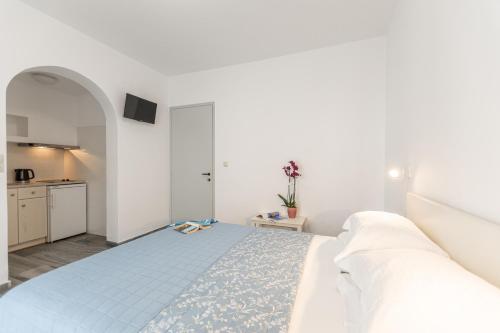 a white bedroom with a bed and a kitchen at Azur Playa Naxos in Naxos Chora
