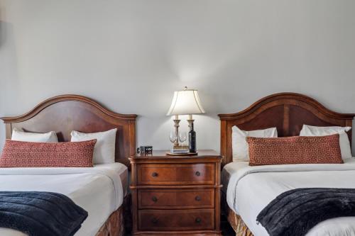 a bedroom with two beds and a lamp on a dresser at Villa Montes Hotel in San Bruno