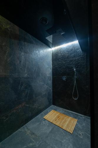 a dark bathroom with a shower with a wooden mat at Private wellness club in Prešov