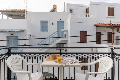 a table with two chairs and a glass of orange juice on a balcony at Azur Playa Naxos in Naxos Chora