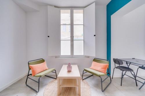 - une chambre avec deux chaises et une table avec un vase dans l'établissement Beau studio confortable Bordeaux, à Bordeaux