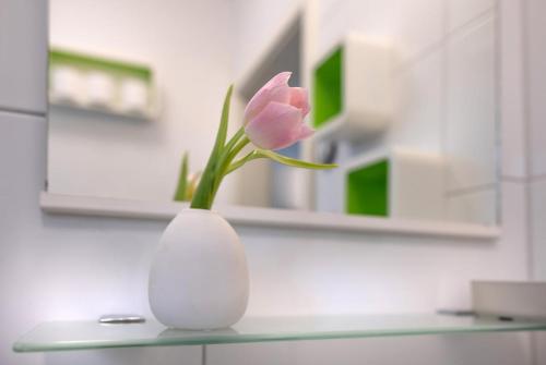 a pink flower in a white vase on a counter at Sonnige, ruhige Gartenwohnung mit Terrasse u. Garten in Oberhaching