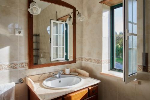 un baño con lavabo y espejo en Chalé da Malvarosa, en Atouguia da Baleia