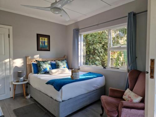 a bedroom with a bed and a window and a chair at MaeStorm Gardens Relax:Reload:Refresh Private room in nature lodge in East London