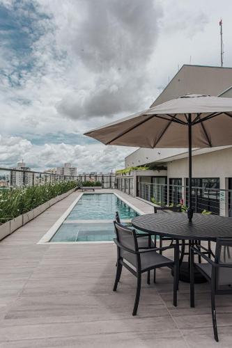 a patio with a table and umbrella next to a pool at Actual - SmartHouse in Uberlândia
