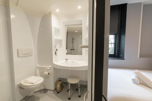 a white bathroom with a toilet and a sink at easyHotel Victoria in London