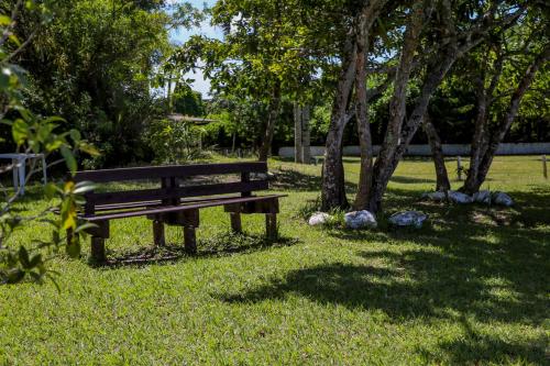 a park bench sitting in the grass under trees at Samburá Chalés in Ilha Comprida