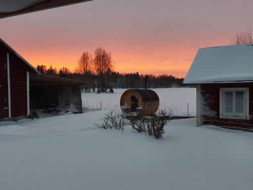 a snow covered yard next to a house with a barrel at Apartment Gasstorp Wifi in Hova