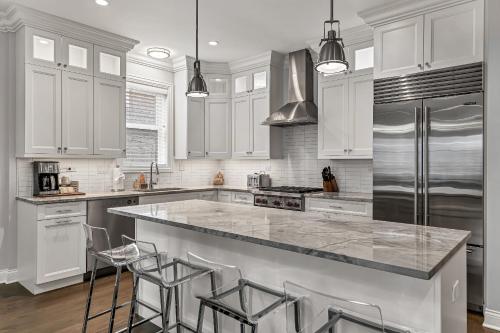 a kitchen with white cabinets and a large island with bar stools at Elegant Condo-Steps from Wrigley Field, 32 Nights condo in Chicago