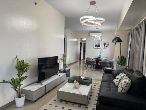 a living room with a black couch and a tv at 175 Sqm Luxurious Modern 3 Bedrooms Facing Manila Bay Sunset, Airports, Okada, Solaire, MOA in Manila