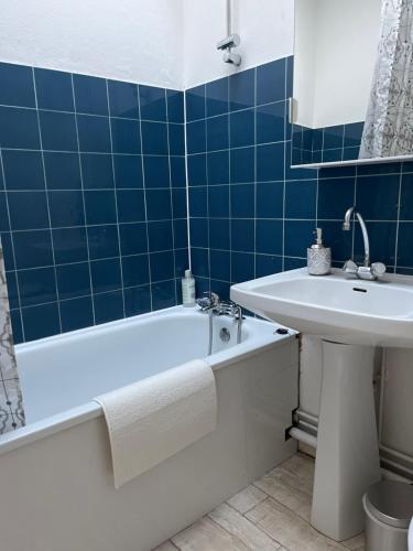 La salle de bains est pourvue de carrelage bleu, d'une baignoire et d'un lavabo. dans l'établissement Appartement centre de Bordeaux, à Bordeaux