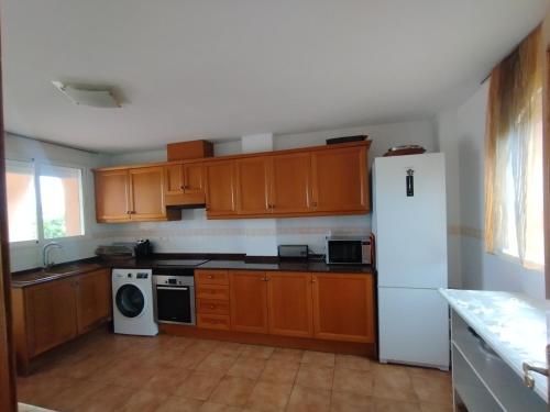 a kitchen with wooden cabinets and a white refrigerator at Valencia, villa, piscina privada, junto A-7 cerca de playas, aeropuerto, Cheste in Torrent