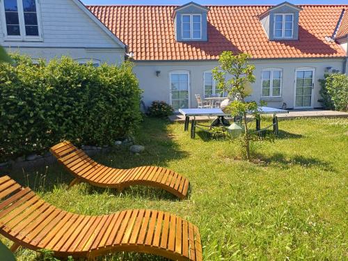 a yard with two wooden benches in the grass at Klintgarden in Martofte