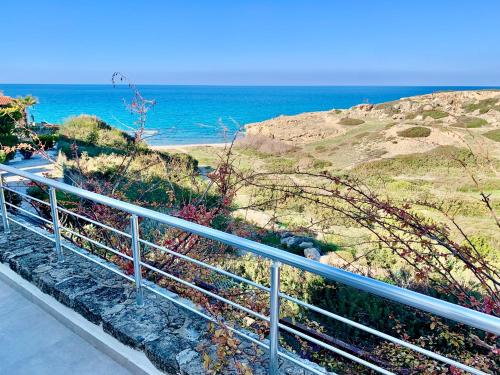 a metal railing next to a beach with the ocean at Boho Bay Apartment in Akanthou
