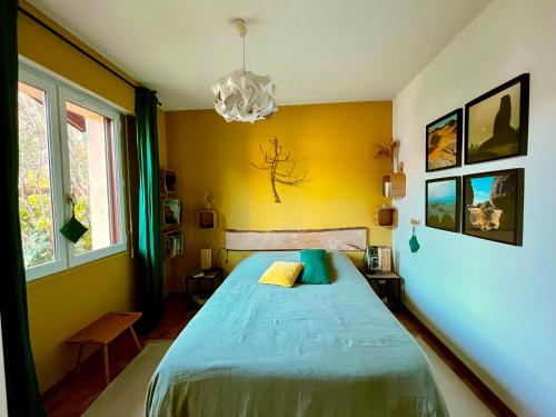 - une chambre avec un lit et un mur jaune dans l'établissement Les Pibales - T2 vue courant à 1.8 km de l'Océan, à Mimizan