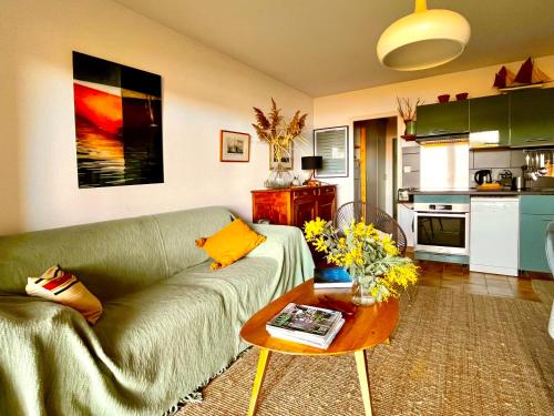 un salon avec un canapé vert et une table dans l'établissement Les Pibales - T2 vue courant à 1.8 km de l'Océan, à Mimizan