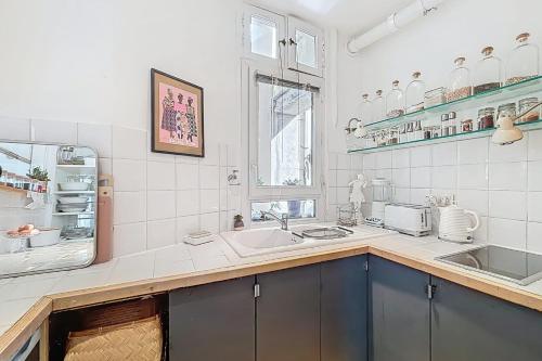 - une cuisine blanche avec un évier et un miroir dans l'établissement Spacious apartment near Bastille & le Marais, à Paris