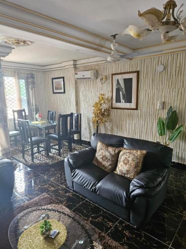 a living room with a leather couch and a table at Rose Garden Apartments in Limbe