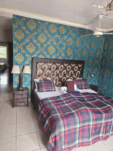 a bedroom with a bed with a plaid blanket at Rose Garden Apartments in Limbe