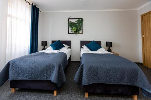 two beds in a hotel room with blue pillows at Noclegi na Wspólnej in Skrzyszów
