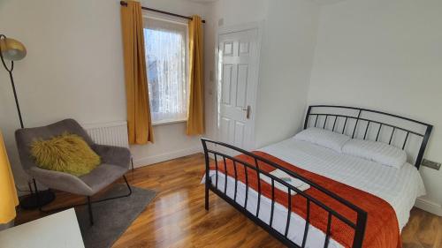 a bedroom with a bed and a chair and a window at Harbour House - Entire Detached 4-BDR, Ensuite and Bath, Fast Speed WiFi, Smart TV, Self Catering - Serving Contractors, Tourists, Santa Pod and Silverstone! in Wymington