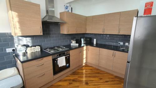 a kitchen with wooden cabinets and a stove top oven at Harbour House - Entire Detached 4-BDR, Ensuite and Bath, Fast Speed WiFi, Smart TV, Self Catering - Serving Contractors, Tourists, Santa Pod and Silverstone! in Wymington