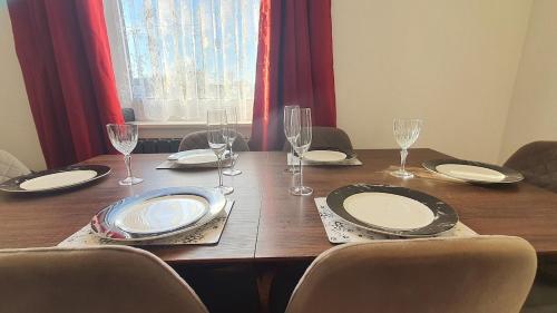 a wooden table with chairs and plates and wine glasses at Harbour House - Entire Detached 4-BDR, Ensuite and Bath, Fast Speed WiFi, Smart TV, Self Catering - Serving Contractors, Tourists, Santa Pod and Silverstone! in Wymington