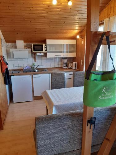 a kitchen with white cabinets and a green bag on a table at Ferienhaus Lerche 3 in Wulfskuhl