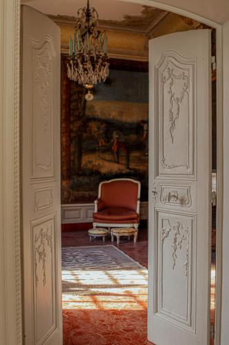 une porte menant à une chambre avec une chaise et un lustre dans l'établissement La Bastide, à Saint-Raphaël
