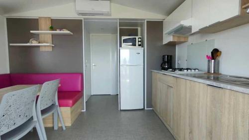 une petite cuisine avec une table et un réfrigérateur dans l'établissement Camping 3 étoiles - Piscine - ccbaega, à Saint-Mitre-les-Remparts