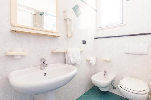 a white bathroom with a sink and a toilet at Hotel De La Ville in Rimini